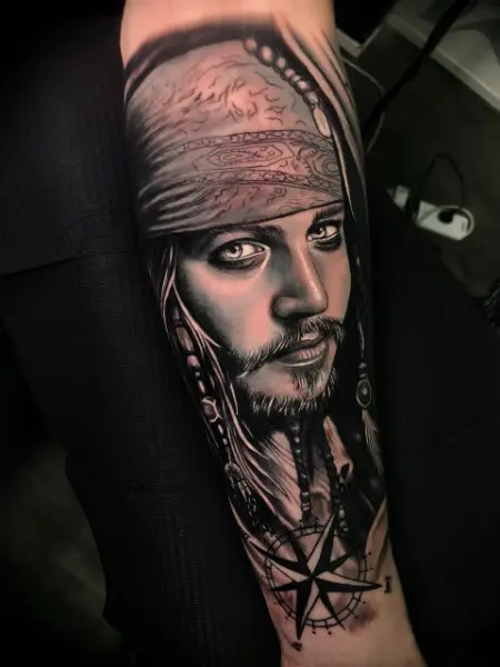 Tatuaje realista black and grey de retrato de pirata con pañuelo, trenzas y abalorios, con rosa de los vientos, en el antebrazo, Buenos Aires