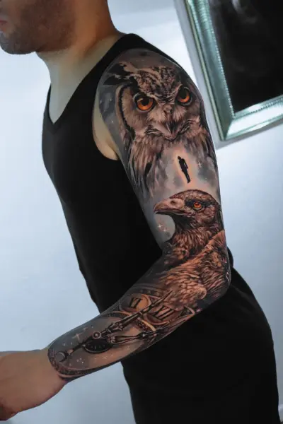 Tatuaje realista de manga completa: búho de ojos naranjas, águila y reloj de números romanos con fondo de estrellas, hecho en Recoleta