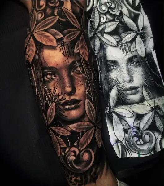 Tatuaje realista black and grey de rostro de mujer con pecas entre hojas y ornamentos, junto a su diseño original, en el brazo, hecho en Recoleta
