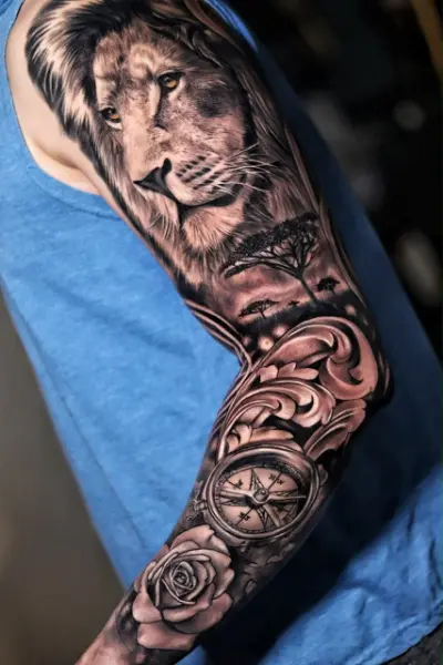 Tatuaje black and grey de manga completa: león de ojos ámbar, sabana africana, ornamentos, brújula y rosa, realismo de brazo entero